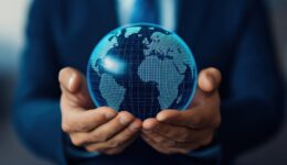 A businessman holds a glowing globe symbolizing global connectivity and innovative solutions in the corporate world.
