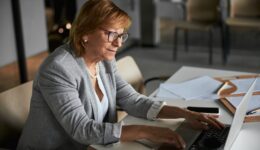Pleased female company director typing on laptop keyboard