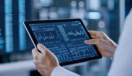 A person is analyzing data on a tablet, displaying graphs and statistics in a high-tech environment.