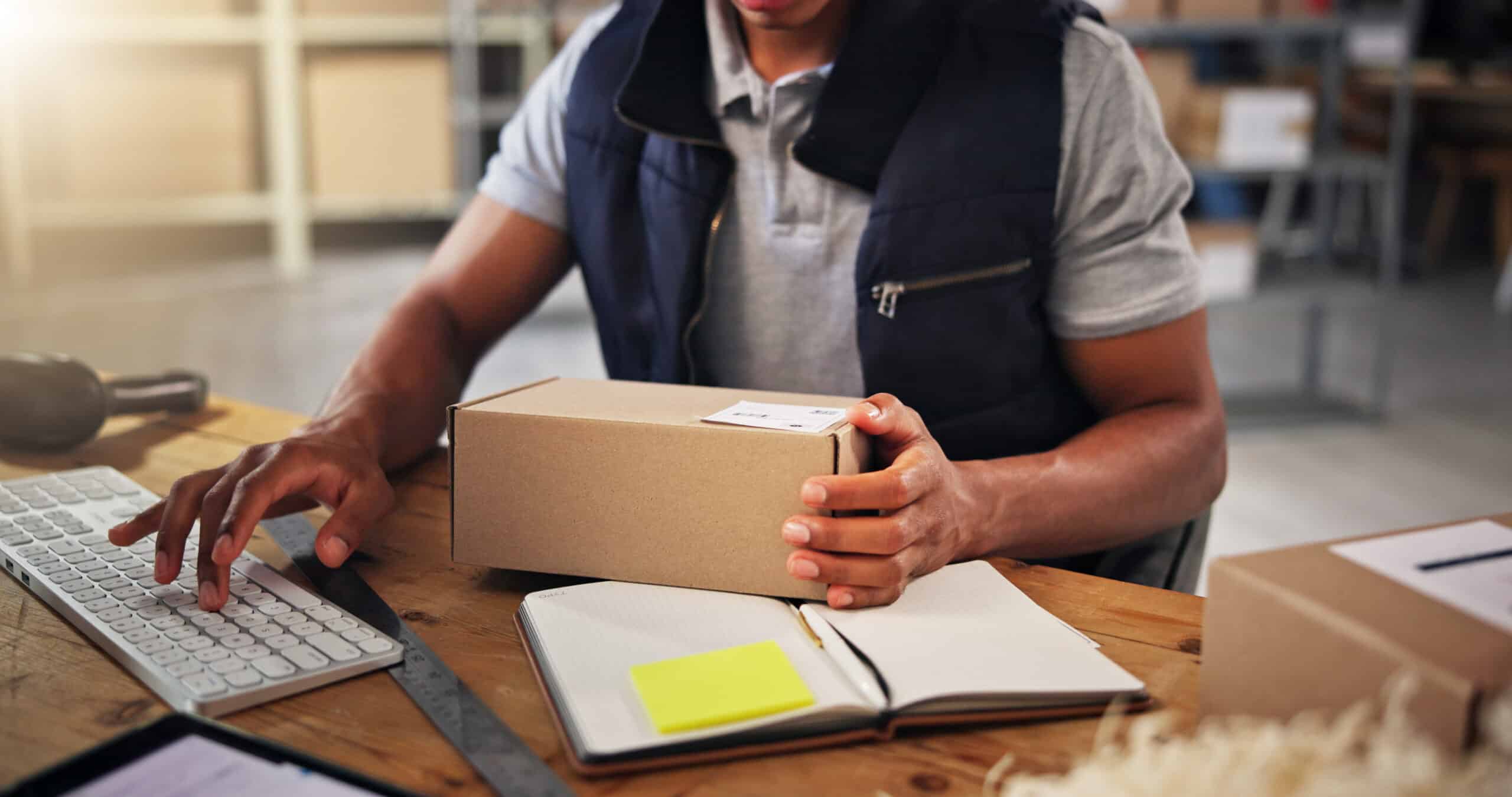 Hands, man typing with box for distribution of inventory management, online order and stock. Person, keyboard and package report of supply chain, quality control and information for delivery schedule