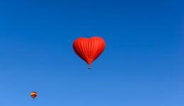 Red heart shaped balloon on the background blue sky.