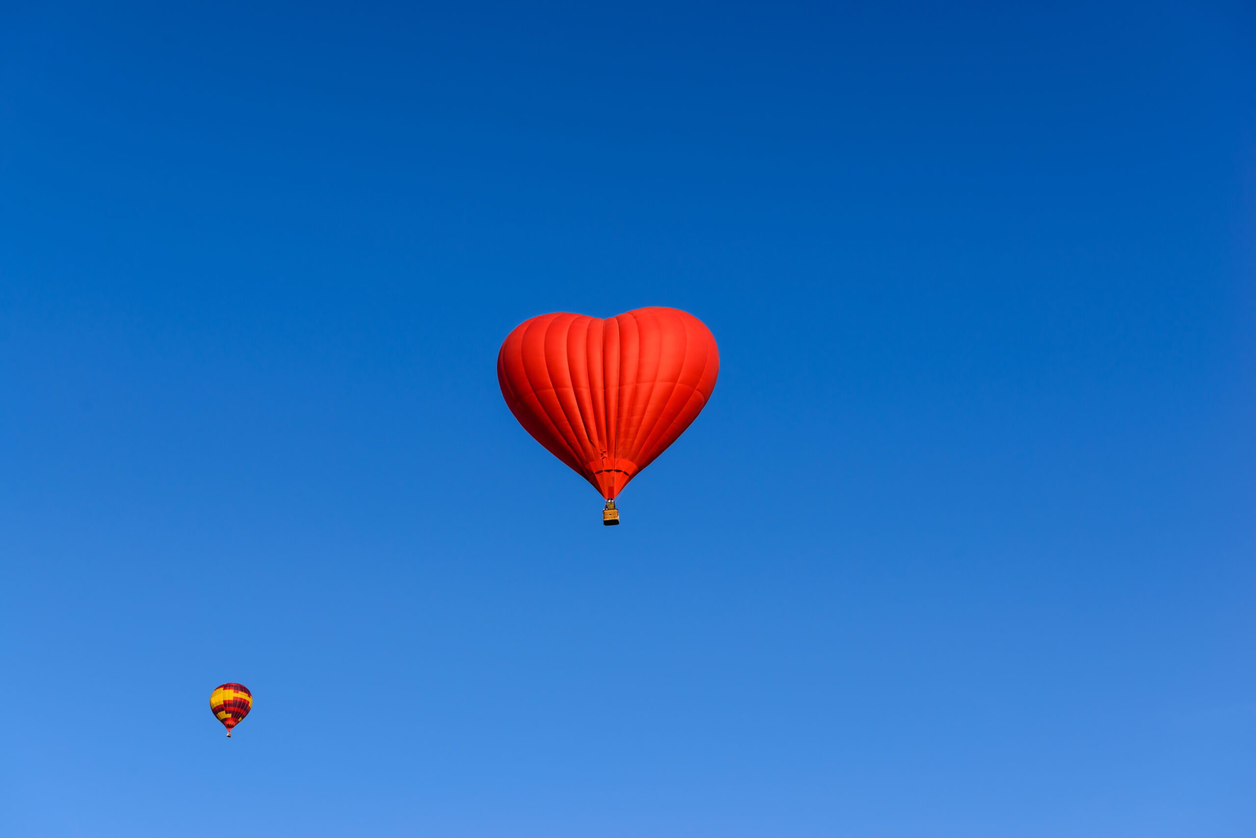 Red heart shaped balloon on the background blue sky.