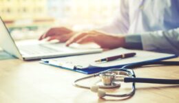 Doctor typing information on Laptop in Hospital office focus on Stethoscope