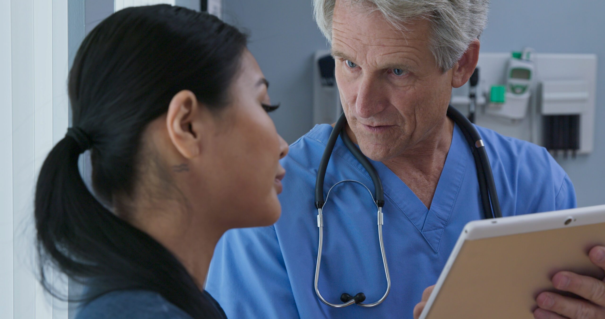 Doctor showing tablet computer with results to patient in hospital exam room