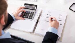 Businessperson Checking Invoice With Calculator