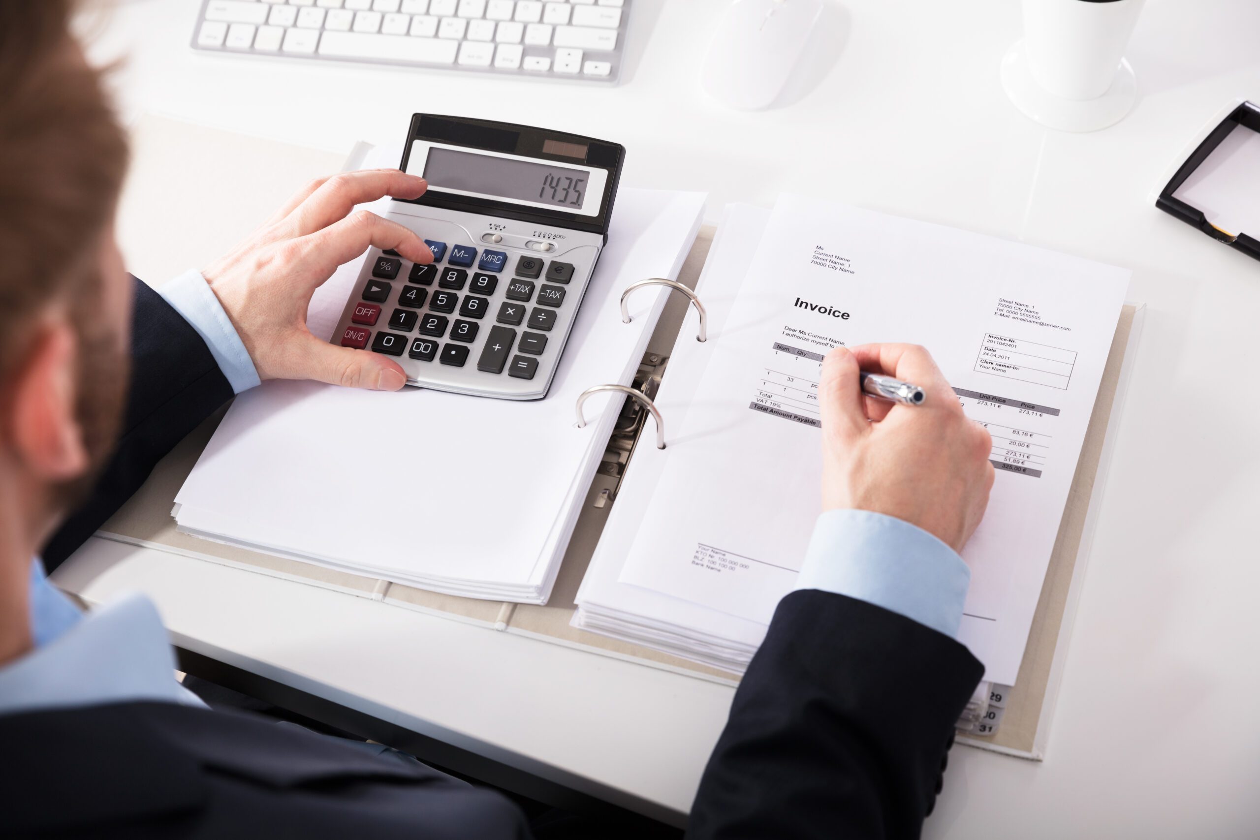 Businessperson Checking Invoice With Calculator