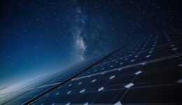 Long-exposure night shot of solar panels under a starry sky with faint moonlight glinting off glass