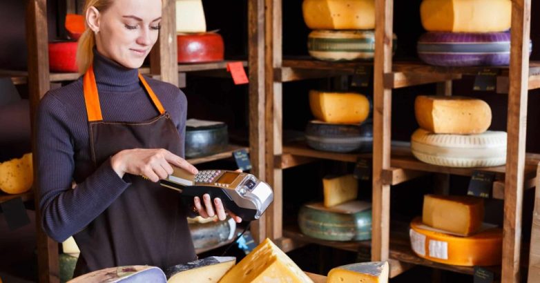 Customer paying for order of cheese in grocery shop.