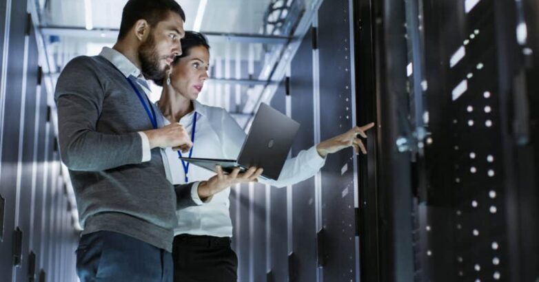 Male IT Specialist Holds Laptop and Discusses Work with Female S