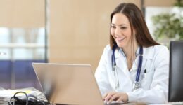 Happy doctor using a laptop at consultation
