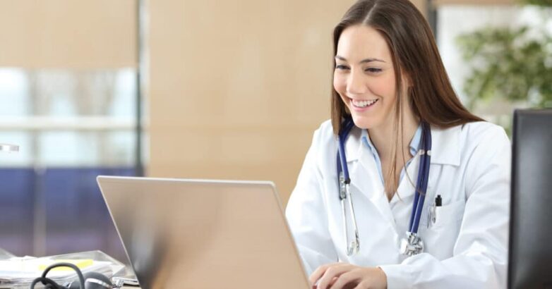Happy doctor using a laptop at consultation