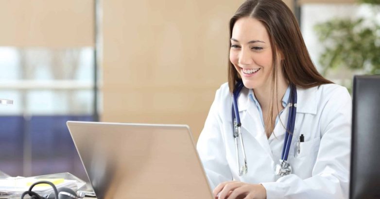 Happy doctor using a laptop at consultation