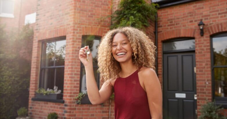 Portrait Of Excited Young Woman Standing Outside New Home Holding Keys Portrait Of Excited Young Woman Standing Outside New Home Holding Keys