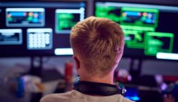 Male Teenage Hacker Sitting In Front Of Computer Screens Bypassing Cyber Security