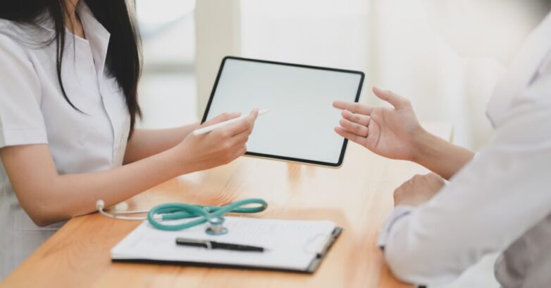 Cropped shot of young female doctor explain symptoms to her patient with tablet Cropped shot of young female doctor explain symptoms to her patient with tablet