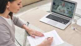 Young woman filling in health insurance form and watching online video