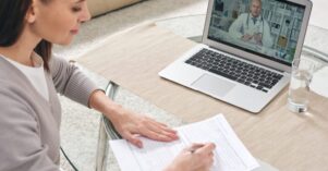 Young woman filling in health insurance form and watching online video Young woman filling in health insurance form and watching online video