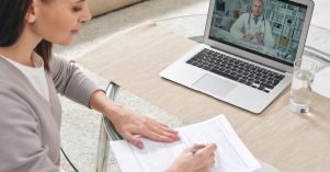 Young woman filling in health insurance form and watching online video Young woman filling in health insurance form and watching online video