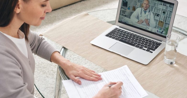 Young woman filling in health insurance form and watching online video