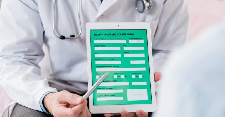 Contemporary doctor in whitecoat pointing at electronic form of health insurance