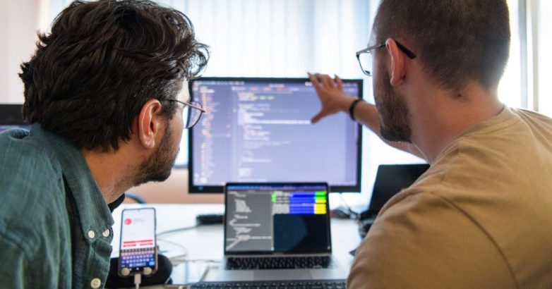 Programmers engrossed in deep collaboration, diligently working together to solve complex problems and develop innovative mobile applications with seamless functionality.