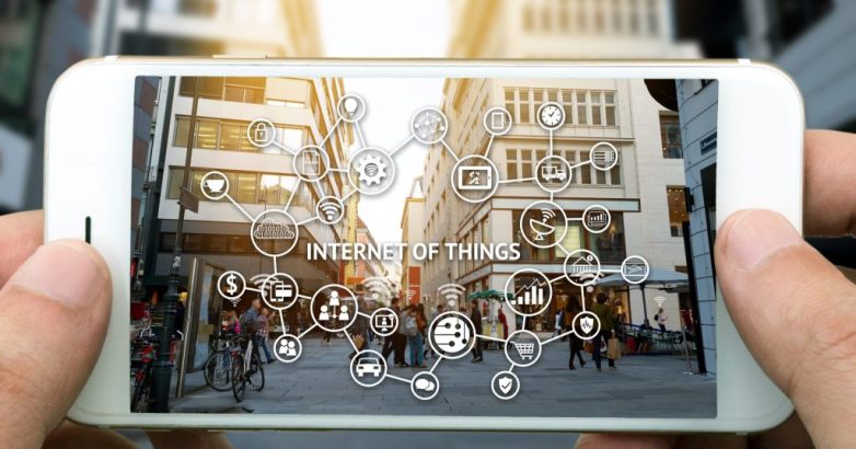 Internet of things (IoT) and digital lifestyle concept . Hand holding smart phone , wifi icons and city view background.