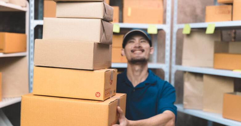 business man in shipping uniform handing customer package prepare for delivery service. man doing work at his small shipping new business and new transportation delivery.