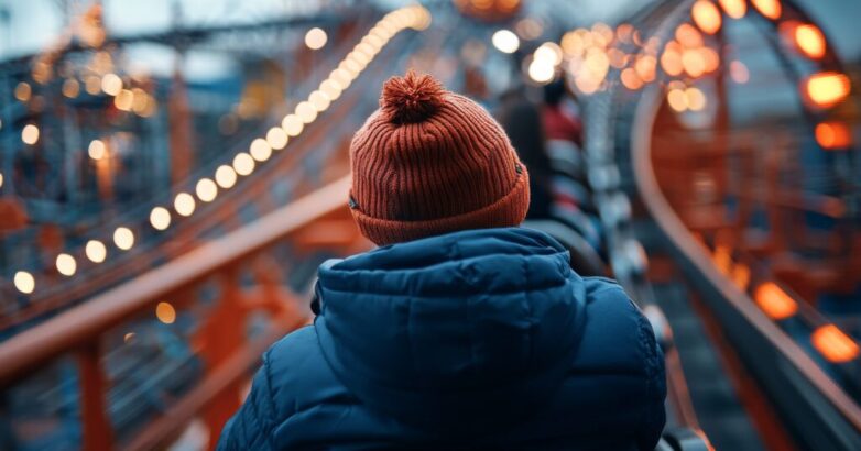 A person wearing a beanie seen from behind, embarking on a thrilling rollercoaster ride at a theme park, with illuminated tracks setting the adventurous mood.