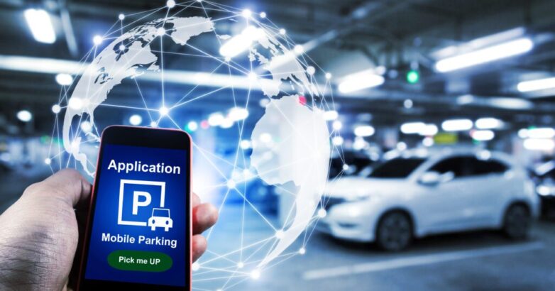 Pick me up, mobile smart phone in hand using application for intelligent car park with digital hologram on blurred parking car background, mobile auto parking, network and online technology concept
