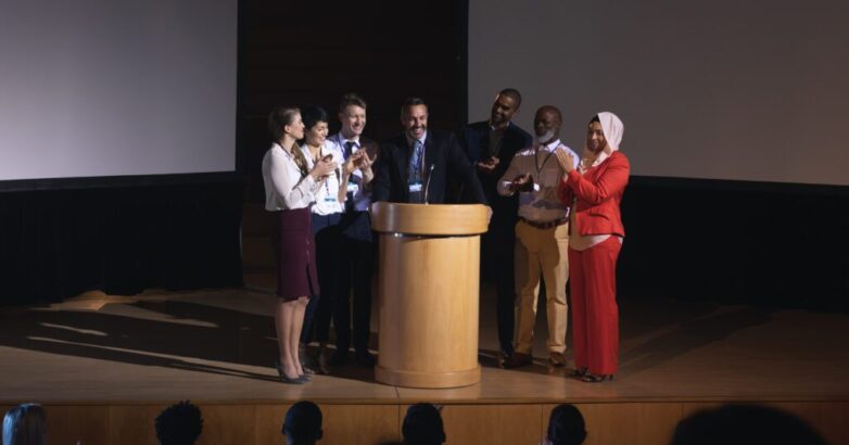 Business colleagues clapping hand for there colleague for the success in the auditorium stage