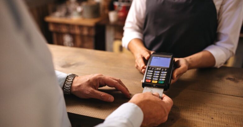 Customer doing payment of coffee by credit card at cafe