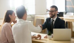 Smiling lawyer or financial advisor handshaking senior couple at