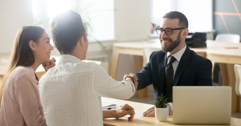 Smiling lawyer or financial advisor handshaking senior couple at