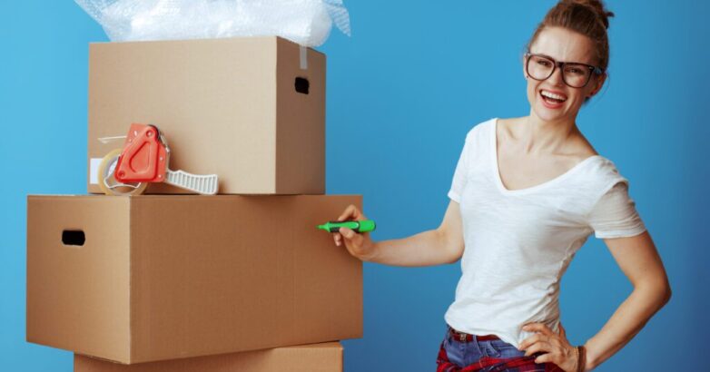 happy young woman in white t-shirt on blue signs cardboard box