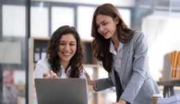 Two young Asian business woman talk, consult, discuss working with new startup project idea presentation analyze plan marketing and investment in the office.