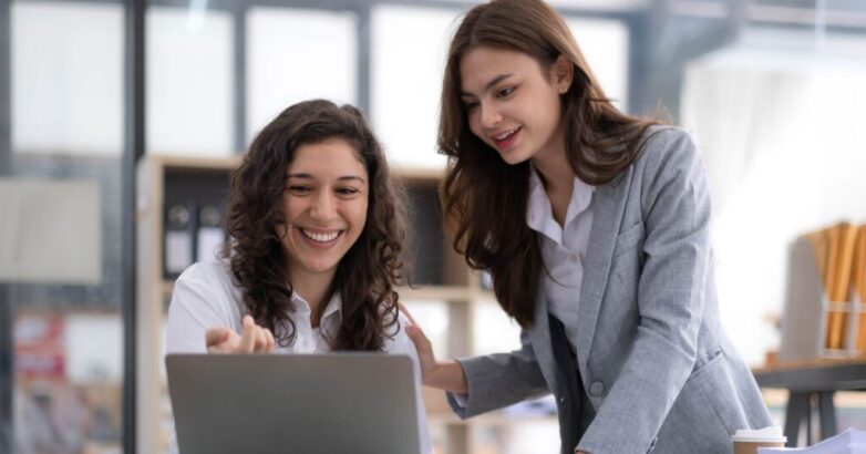 Two young Asian business woman talk, consult, discuss working with new startup project idea presentation analyze plan marketing and investment in the office.