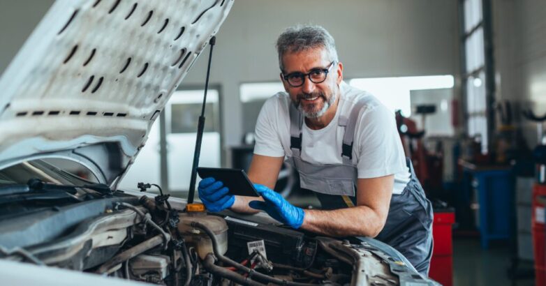 checking online for car spare parts . worker using tablet in car workshop