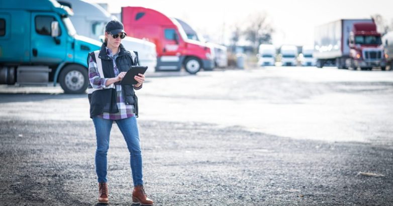 Woman truck driver transportation professional walking in truck yard