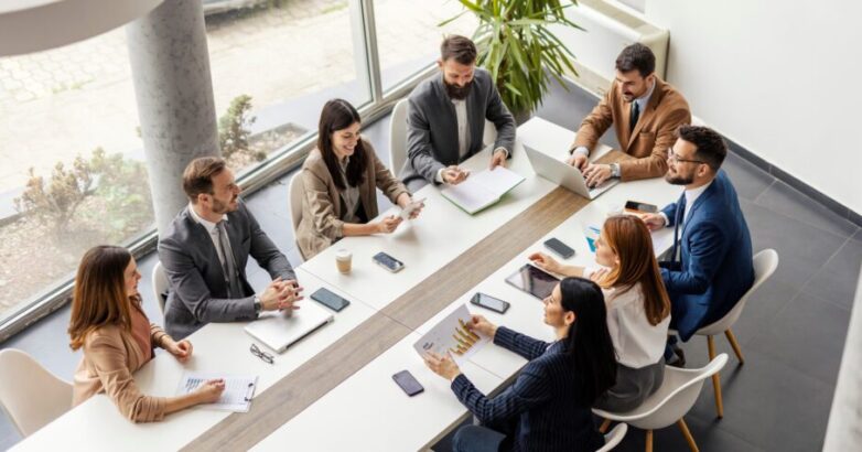 Top view of group of businesspeople sitting at boardroom and discussing data analytic. Top view of group of businesspeople sitting at boardroom and discussing data analytic.