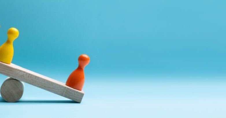 Red And Yellow Pawns Figures Balancing On Wooden Seesaw Red And Yellow Pawns Figures Balancing On Wooden Seesaw